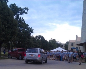 cars surrounded by move crew volunteers in gray T-shirts